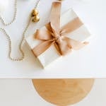 Top view of a beautifully wrapped gift with gold decorations on white surface.